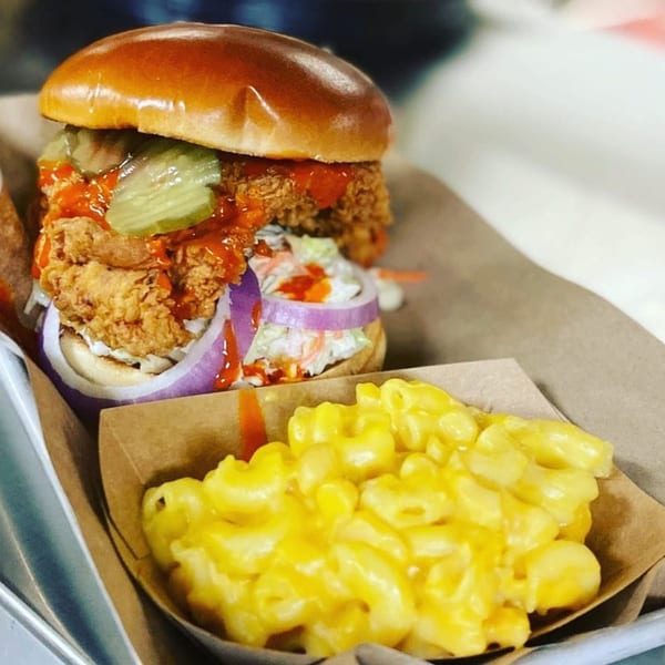 Spicy fried chicken sandwich with pickles, coleslaw, and red onion, served with mac and cheese.