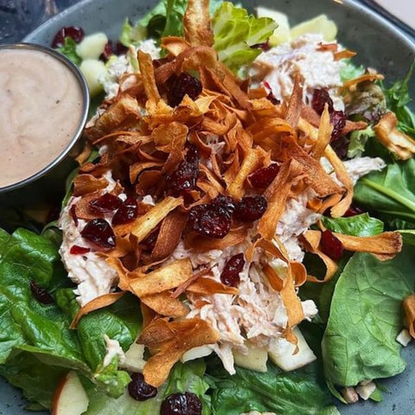 A close-up of a Sticky Fingers Rib House salad with chicken, dried cranberries, and crispy fried onions.
