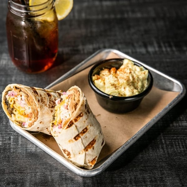 Two grilled wraps with mac and cheese, served with a side of mac and cheese and iced tea.