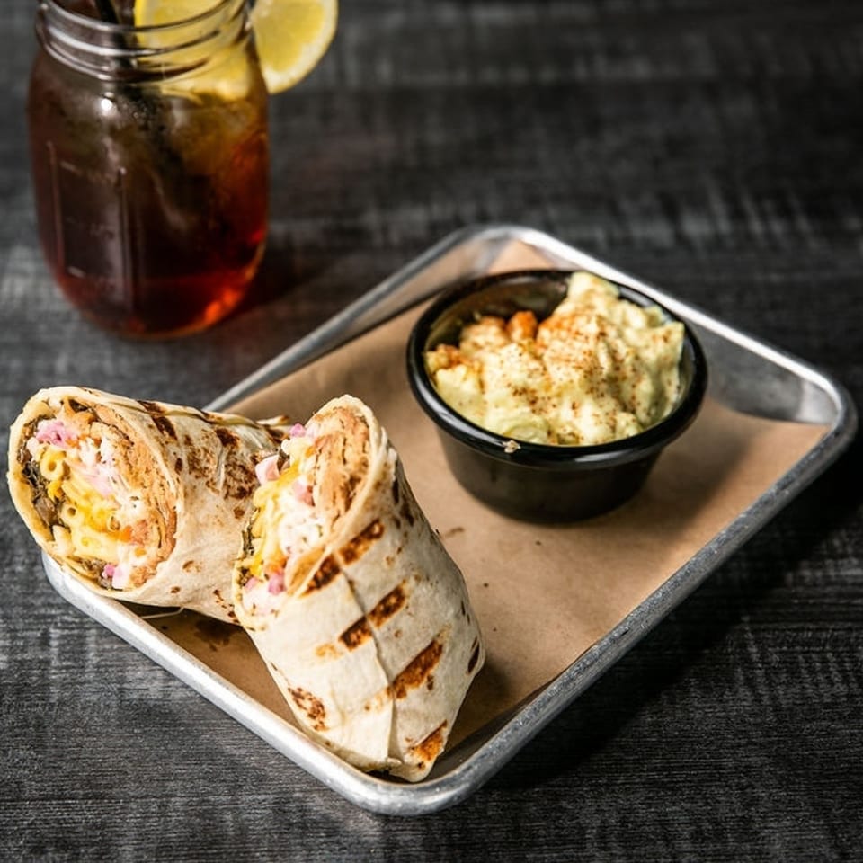 Two grilled wraps with mac and cheese, served with a side of mac and cheese and iced tea.